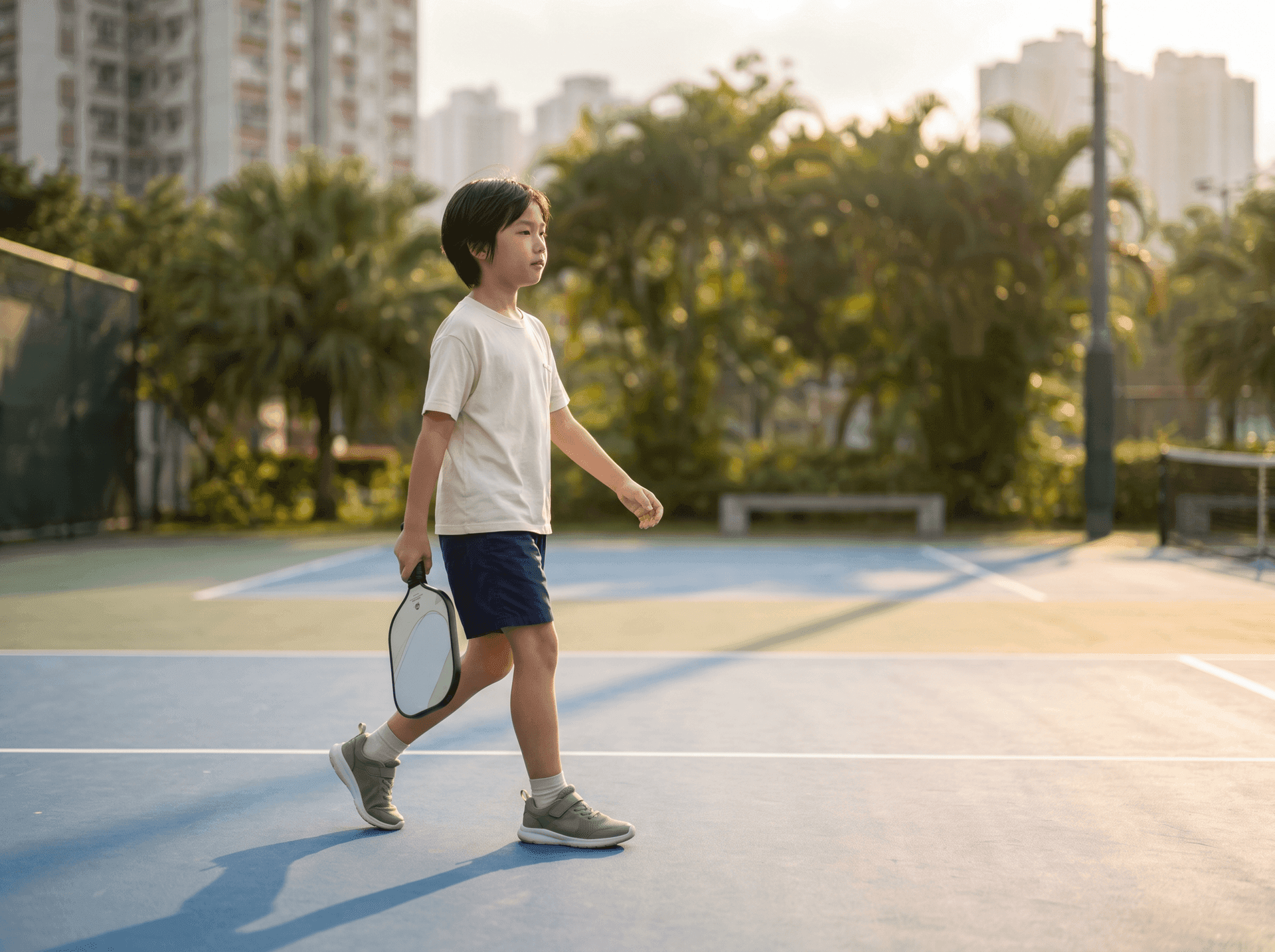 Kid moving easily across an outdoor pickleball court