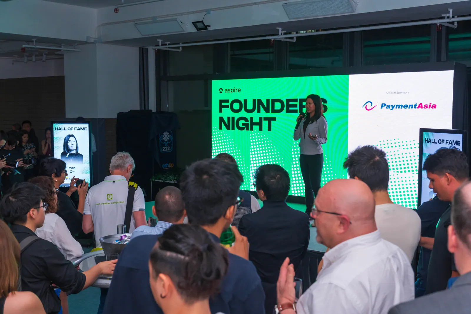 A founder on stage in front of the Founders Night LED wall at a corporate event hosted at 212HK